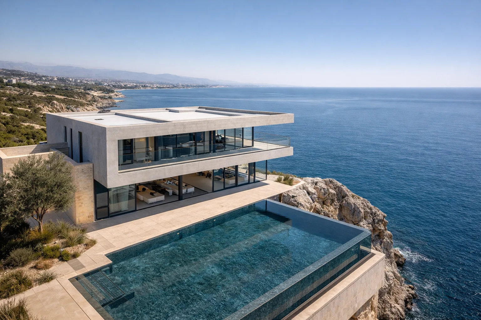 Aerial 45-degree drone shot showing the cliff-edge positioning, infinity pool merging with the sea, and Limassol coastline